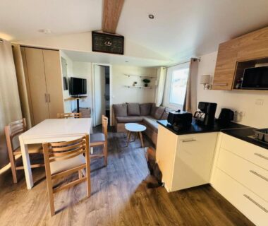 Intérieur du séjour avec canapé et kitchenette dans le camping Bienvenue chez Jean