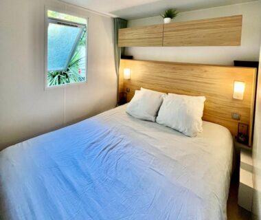Chambre avec lit double et fenêtre sur jardin dans le mobil-home Bisca wifi