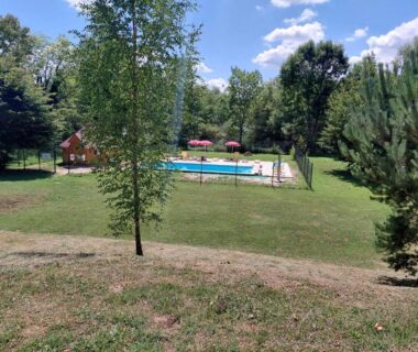 Pelouse et piscine clôturée parmi les arbres au camping Bleu d'Argonne