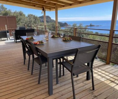 Terrasse couverte avec table à manger et vue sur la mer au camping Blue Horizon