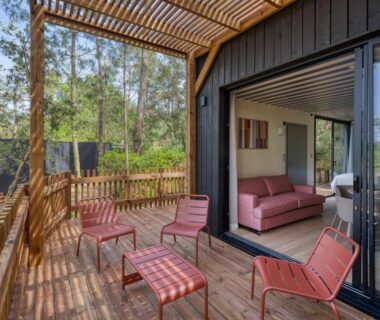 Terrasse en bois avec chaises et salon intérieur ouvert au camping Bonjour Sauvage Seignosse