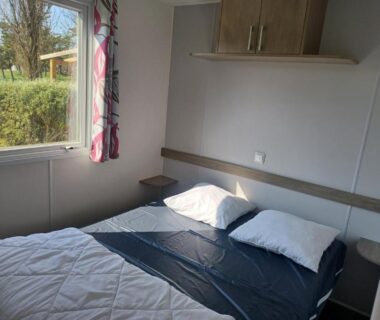 Chambre avec lit double et fenêtre donnant sur la végétation du camping Bora Bora