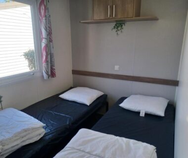Chambre avec deux lits simples, fenêtre et étagère du camping Bora Bora