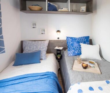Chambre avec deux lits et linge bleu dans le Bungalow Bord de mer