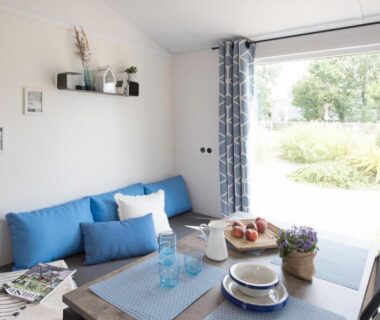 Salon avec table dressée et baie vitrée donnant sur le jardin du Bungalow Bord de mer