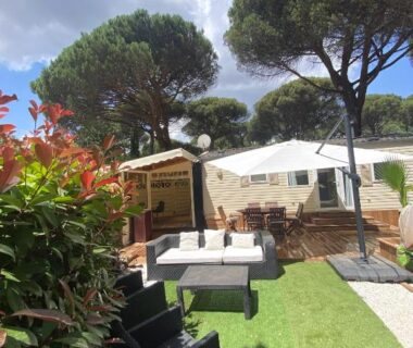 Terrasse ombragée sous pins avec salon extérieur au Bungalow Camping Parc Montana