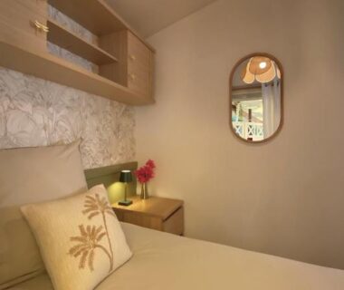 Chambre avec lit coussin décoratif lampe et miroir dans le Bungalow Camping Parc Montana
