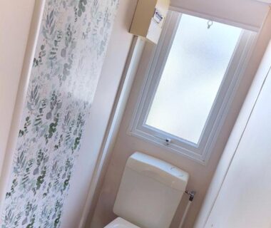 Toilettes compactes avec fenêtre et papier toilette dans le Bungalow Cosy équipé