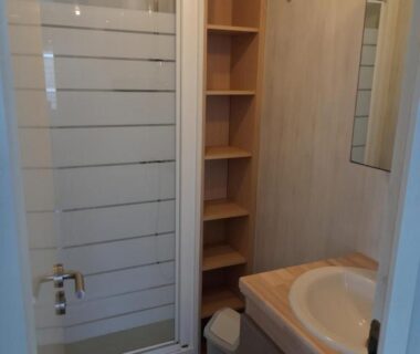 Salle de bain avec cabine de douche lavabo et étagères dans le Bungalow Natherem