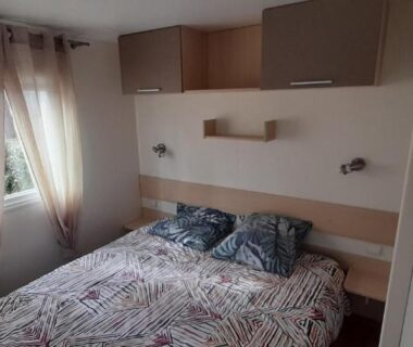 Chambre avec lit double et rideaux clairs dans le Bungalow Natherem