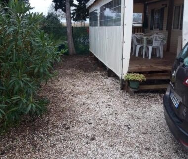 Allée gravillonnée et terrasse couverte avec chaises plastique au Bungalow a hyeres