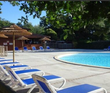 Piscine extérieure avec transats et parasols au Bungalow bord de Lac Biscarosse