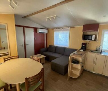 Intérieur avec canapé table à manger et kitchenette dans le Bungalow camping Bel Air Village