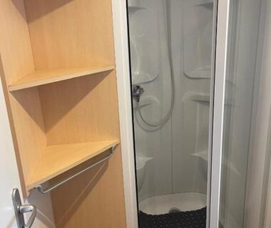 Salle d'eau avec cabine de douche et étagères dans le bungalow camping la Berge fleurie