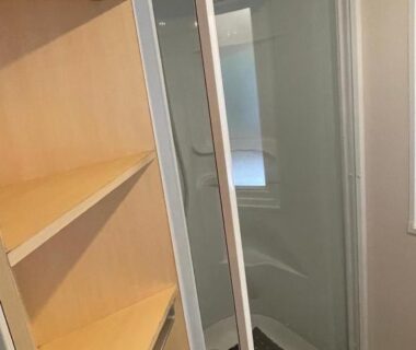 Salle de bains avec cabine de douche et étagères dans le bungalow camping la Berge fleurie