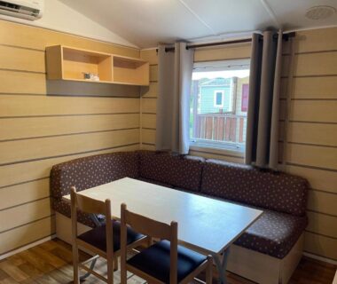 Intérieur coin repas avec banquette et table dans le Bungalow camping la Berge fleurie