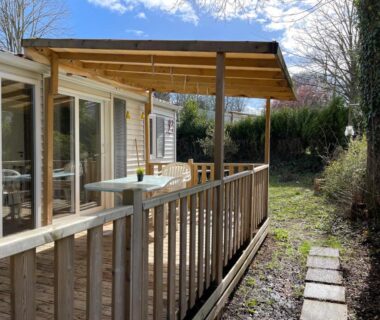 Terrasse couverte avec table et baie vitrée au Bungalow climatisé dans un bel écrin de nature