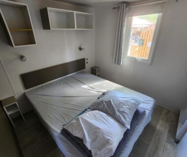 Chambre avec lit double, étagères et fenêtre dans le Bungalow confort du Camping 4 étoiles Canet Front de mer