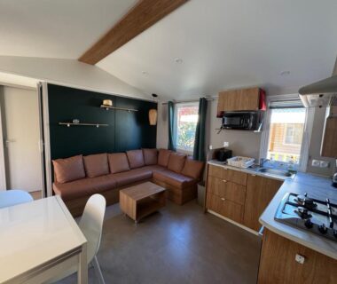 Intérieur salon avec canapé et kitchenette dans le Bungalow jardin les Viviers cap-ferret