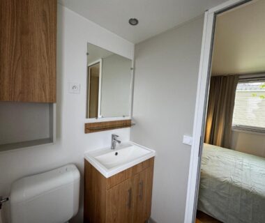 Salle de bain avec lavabo miroir toilette et aperçu de la chambre du Bungalow moderne vue bassin les viviers Cap-ferret