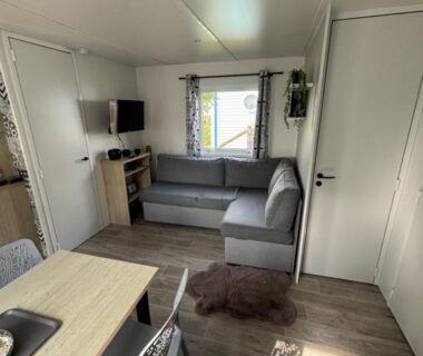 Intérieur du bungalow avec canapé, table à manger et télévision du Bungalow tout confort 6 personnes