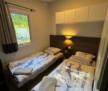 Chambre avec deux lits simples et lampe de chevet dans le bungalow vue mer jacuzzi terrasse jardin