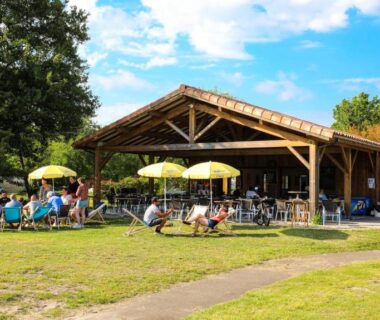 Terrasse couverte avec parasols et transats sur la pelouse au Camping Azu'Rivage