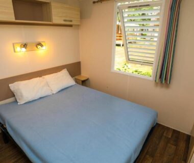 Intérieur chambre double avec lit et fenêtre dans le mobile home du CAMPING AZU'RIVAGE