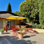 Terrasse extérieure avec parasol jaune et chaises rouges au CAMPING GINASSERVIS Mobile-home Flores