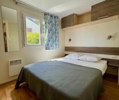 Chambre double lumineuse avec lit et fenêtre dans le mobil-home Flores au CAMPING GINASSERVIS