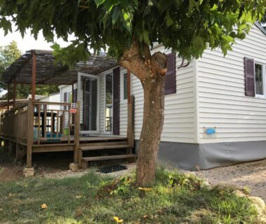 Terrasse en bois ombragée avec arbre devant le mobile-home Flores au Camping Ginasservis