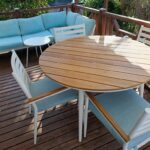 Terrasse en bois avec table ronde et fauteuils bleus au camping Le Clos du Thym