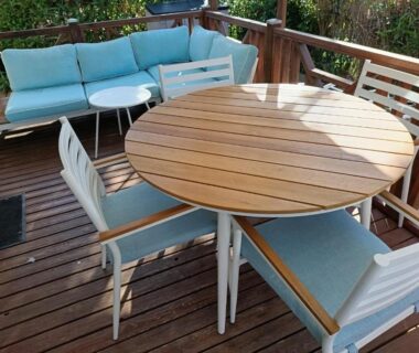 Terrasse en bois avec table ronde et fauteuils bleus au camping Le Clos du Thym