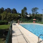 Piscine extérieure avec solarium et parasol au Camping Le Saillet Lestelle Betharram