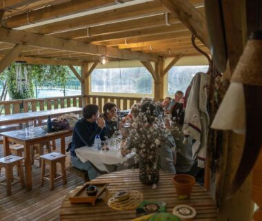 Terrasse couverte en bois avec tables et convives au Camping Le Saillet Lestelle Betharram