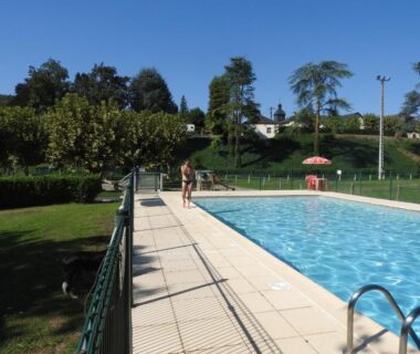 Piscine extérieure avec solarium et parasol au Camping Le Saillet Lestelle Betharram