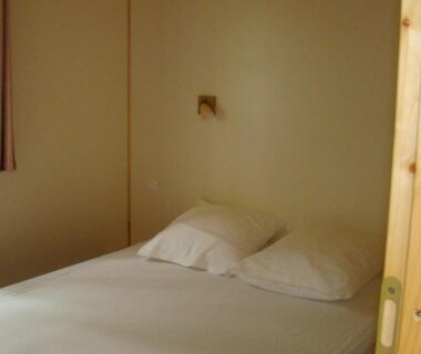 Chambre avec lit double et fenêtre au Camping Les Graves