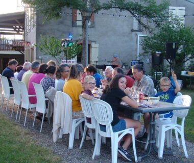 Jardin extérieur avec grande table et convives au Camping Les Graves
