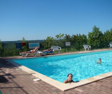 Piscine extérieure avec transats et vue sur la campagne au Camping Les Graves Cabane Tithome