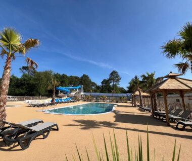 Bord de piscine avec toboggan et transats au Camping Les Ourmes Hourtin