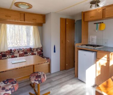 Intérieur avec coin repas et kitchenette dans le mobil-home du CAMPING LES PAILLOTES