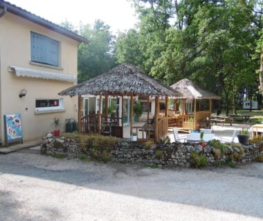 Terrasse extérieure avec kiosques en bois et tables au Camping Les Paillotes