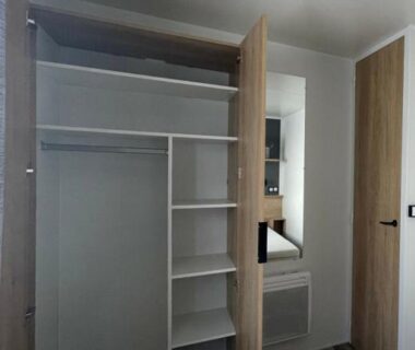 Placard ouvert avec miroir dans la chambre du CAMPING Les EMBRUNS