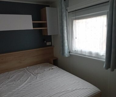 Chambre avec lit double et fenêtre dans l'hébergement du Camping Les EMBRUNS 4 étoiles
