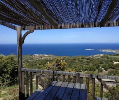 Terrasse ombragée avec table et vue panoramique sur la mer au Camping Monte Ortu