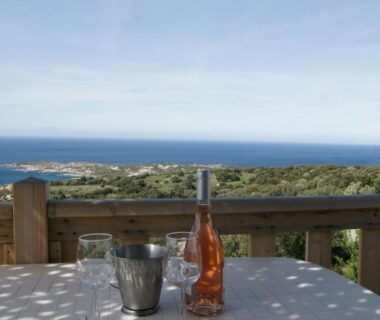 Terrasse avec bouteille et verres face à la mer au Camping Monte Ortu