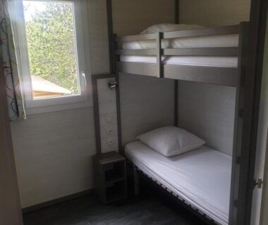 Chambre avec lits superposés et fenêtre dans l'hébergement du CAMPING MUNICIPAL LA SAPINETTE