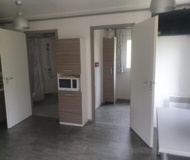 Intérieur avec kitchenette micro-ondes douche et télévision du camping municipal La Sapinette
