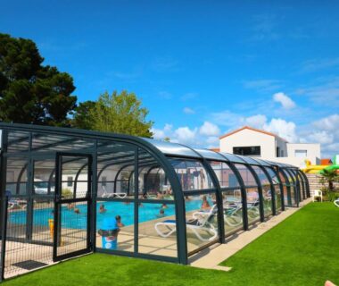 Piscine couverte et pelouse avec transats au Camping Paradis Domaine Oyat