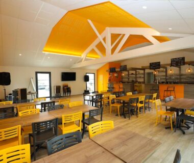 Salle de restauration intérieure avec tables et bar au CAMPING PARADIS Domaine Oyat